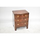 A 1950s walnut serpentine fronted chest of three drawers, raised on bracket feet, width 61cm,