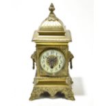 A late 19th century French brass cased thirty day mantel clock, with twin beast masks suspending