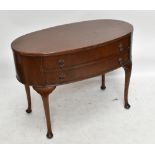 An early 20th century oak dressing table of oval form, with two drawers, raised on cabriole supports