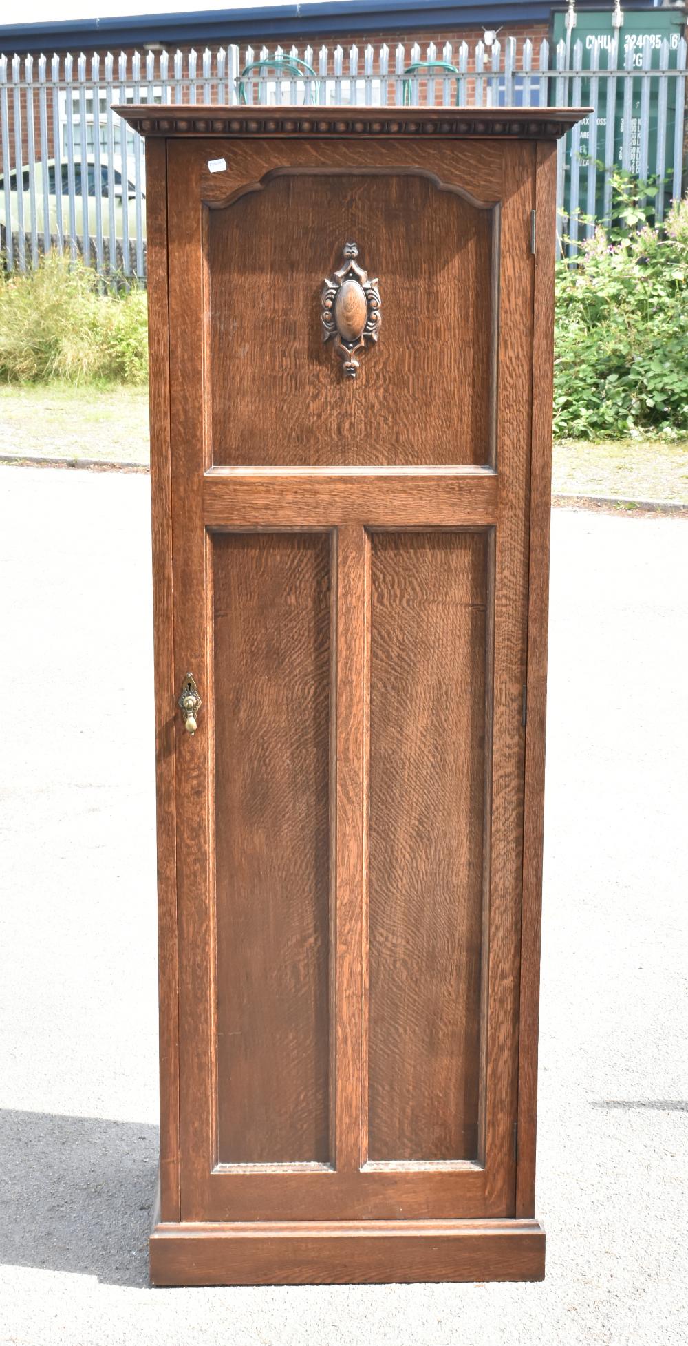 THE VERITHING; a 1950s oak hall robe, the single panelled door with carved detail to the top