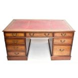 A reproduction oak veneered twin pedestal kneehole desk, with maroon leather inset top above an