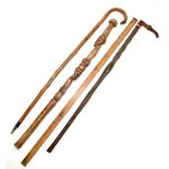 A carved softwood tribal walking stick decorated with two male masks, length 85.5cm, with an