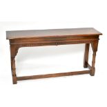 A reproduction oak console table with carved stretcher, raised on turned column supports, width