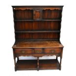 A reproduction oak dresser, the boarded plate rack back with central cupboard door above two fixed