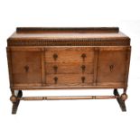 An early 20th century oak sideboard with twin dentil carved brush slide drawers above three short