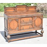 A 1920s carved oak sideboard with panelled back section above two central drawers flanked by two