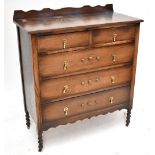 A 1920s oak chest of drawers with wavy gallery back above two short over three long drawers,