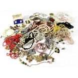 A bag containing various items of costume jewellery to include brooches, fashion watch, necklaces,