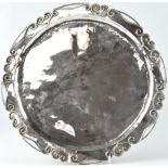 An Elizabeth II Arts & Crafts style hallmarked silver tray of hand beaten circular shape,