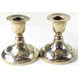 A pair of George V hallmarked silver squat candlesticks with floral petal design,