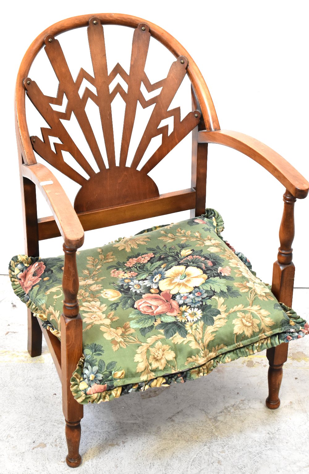 An early 20th century Arts & Crafts style low chair, cut-out fretwork, sunburst back to curved arms,