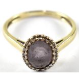 A 9ct gold diamond and amethyst ring, the central purple stone set within a circle of tiny diamonds,