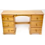 A 20th century pine kneehole desk with six drawers, raised on bun feet, width 132cm.