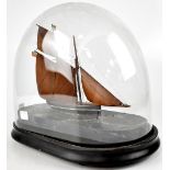 A two masted sailing ship with wooden sails and British ensign on an oval marbled base,