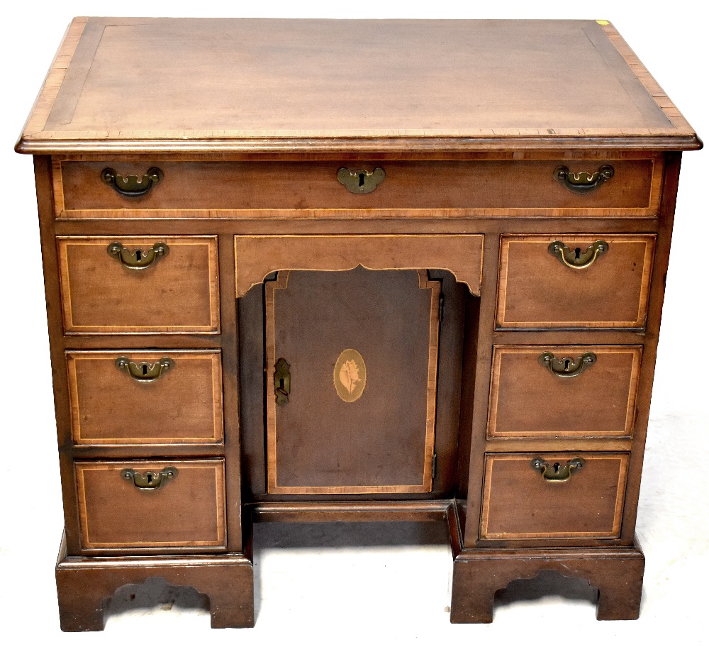 A George III mahogany kneehole writing desk with string inlaid lift-up top enclosing a