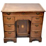 A George III mahogany kneehole writing desk with string inlaid lift-up top enclosing a