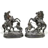 AFTER GUILLAUME COUSTOU; a pair of bronzed spelter Marly Horses, raised on oval wooden plinth bases,