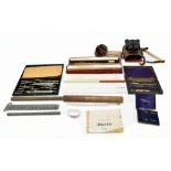 A collection of boxed measuring and drawing instruments including numerous rules, also a leather