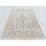 A Persian hand knotted wool Kashan carpet decorated with overall foliate motifs against a beige