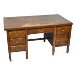 A 1950s oak kneehole desk with an arrangement of seven drawers, raised on tapering block supports,