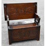 A 1920s carved and stained oak monk's seat, with hinged top and arms carved as lions, with box seat,