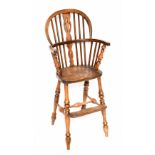 A reproduction elm child's Windsor high chair raised on turned column supports, height 86cm.