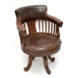 An early 20th century oak framed swivel captain's armchair with leather back and seat cushion,
