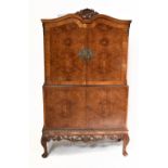 A 1950s burr walnut veneered cocktail cabinet, the top pair of cupboard doors enclosing a mirrored