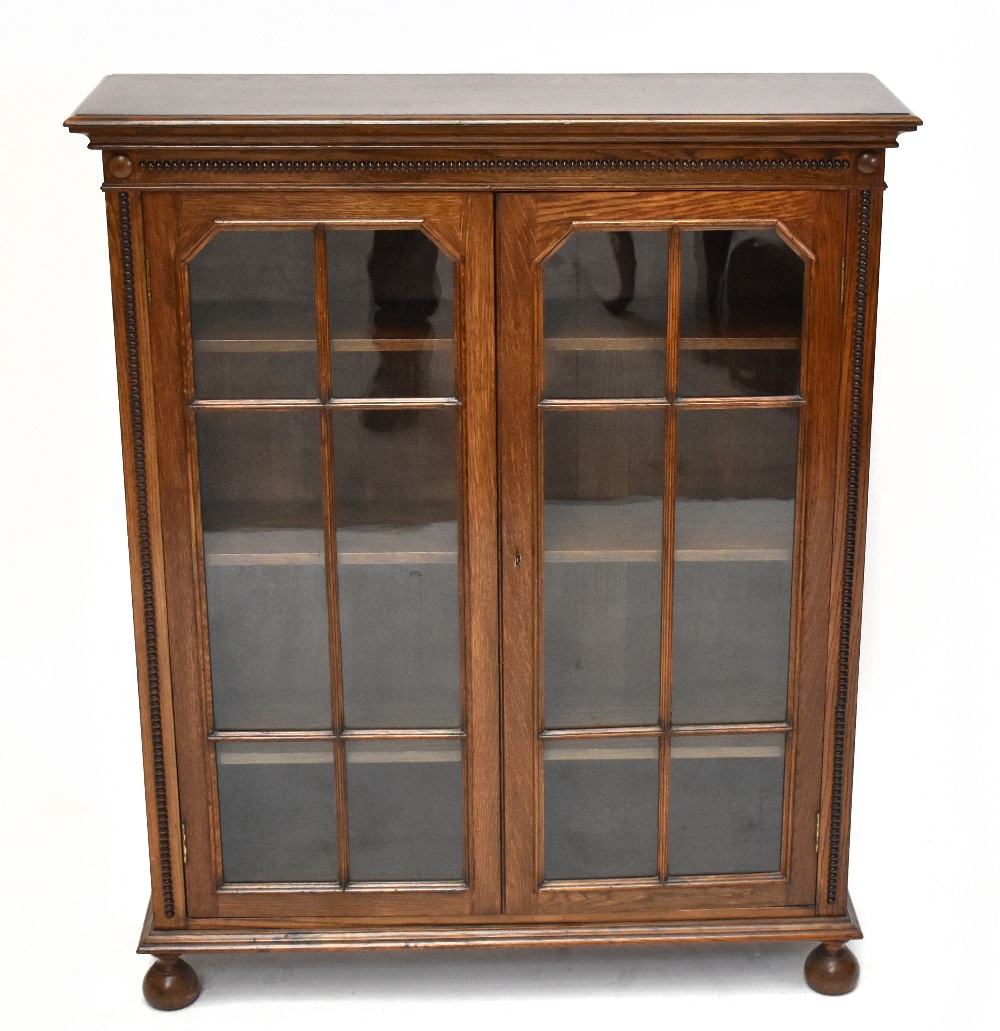 An early 20th century oak bookcase, with two astragal glazed doors, on bun feet, height 110cm, width