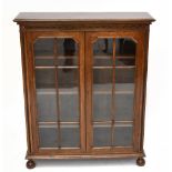 An early 20th century oak bookcase, with two astragal glazed doors, on bun feet, height 110cm, width