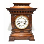 JUNGHANS; a late 19th century carved walnut bracket clock, the circular white enamelled dial with