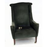 An Edwardian George III style wing armchair, with green dralon upholstery on tapered square legs,