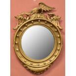 A Regency carved giltwood and gesso wall mirror with eagle surmount above a circular plate within