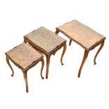 A 1950s walnut nest of three graduated coffee tables, with carved edge and raised on carved cabriole