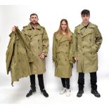 Four WWII era United States dispatch rider long coats in khaki cloth, one with stencilled numerals