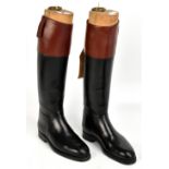 A pair of black leather hunting boots with tan leather tops, each with sectional boot trees for