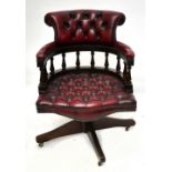 A reproduction office swivel chair, with button back red leather upholstered back, arms and seat, on