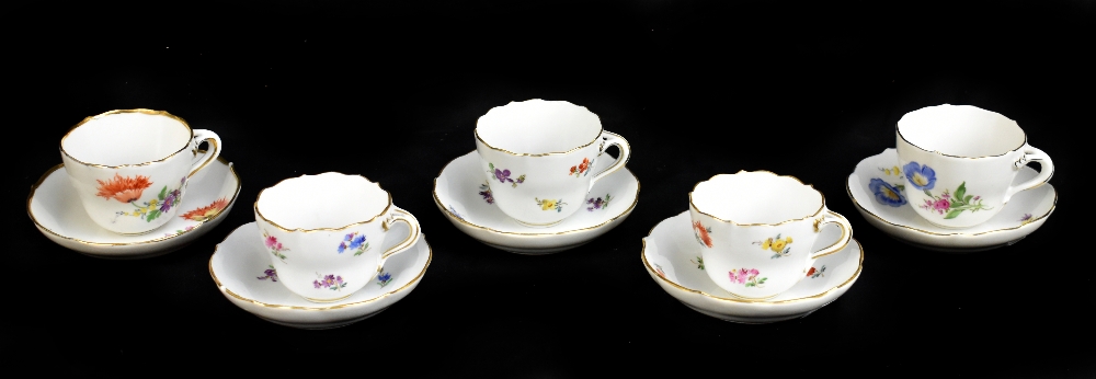 MEISSEN; a harlequin set of five porcelain cups and saucers, each decorated with floral sprigs under