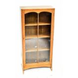 A 1920s light oak narrow bookcase, with glazed door on standard end supports, height 114cm, width