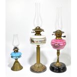 A Victorian oil lamp with pink opaque glass reservoir, raised on brass column terminating on a black