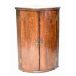 A George III oak and mahogany crossbanded bowfronted corner cabinet, with fluted side details,