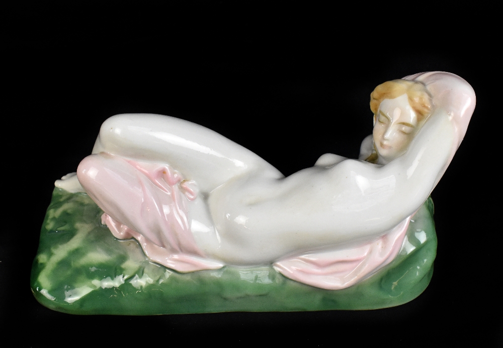 ZSOLNAY PECS; an early 20th century figure of a reclining partly draped nude female, raised on green