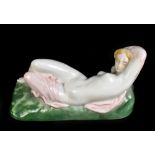 ZSOLNAY PECS; an early 20th century figure of a reclining partly draped nude female, raised on green