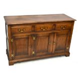 A reproduction oak sideboard with three drawers above three panelled cupboard doors, each with H
