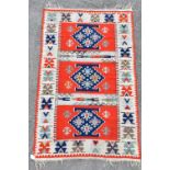 A Russian Eastern style rug with geometric decoration on a red and beige ground, 141 x 89cm.