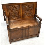 A 1950s oak monk's bench, with carved back panel above hinged seat enclosing storage compartments,