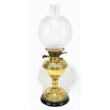 A late 19th century brass oil lamp with foliate scroll relief detail, etched globe in clear chimney,