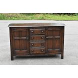A 1930s stained oak sideboard, with four central drawers flanked by two panelled cupboard doors,