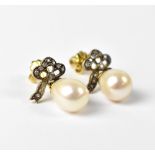 A pair of yellow metal drop earrings, a diamond set bow with single pearl drop.