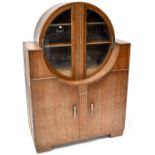 An Art Deco limed oak display cabinet, upper round section with pair of bevelled glass doors,